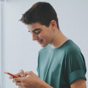 Teen boy looking down at his phone, smiling