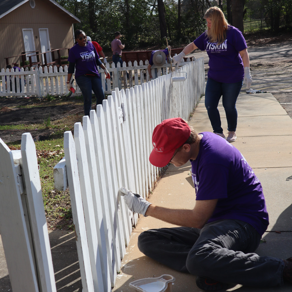 Photo of three volunteers repainting a fence
